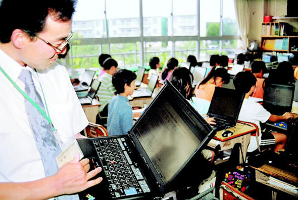 무선랜 환경을 갖춘 일본 나미키초등학교의 구보다 요시히코 교사가　5학년 2반 교실에서 노트북으로 개인별 맞춤 수업을 진행하면서 학생들이 풀고 있는 문제를 살펴보고 있다.