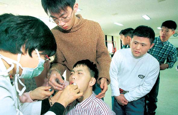 장애복지시설을 돌며 무료진료 활동을 벌이고 있는 서울시립아동병원 의료진이 최근 한 장애인 시설을 방문해 어린이들을 상대로 치과 진료를 하고 있다. 이정우 기자 <A href=\"mailto:woo@hani.co.kr\">woo@hani.co.kr</A>