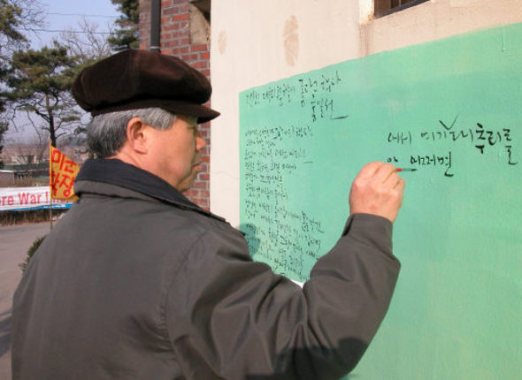 시인 홍일선씨가 25일 오후 경기도 평택 대추리에서 열린 평화문예축전에 참가해 담벽에 자신의 시 <당신은 대추리 푸른 하늘이 좋다고 했다>를 적어 넣고 있다.
