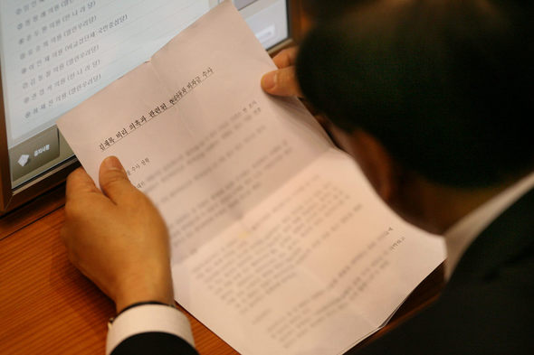 이재오 한나라당 원내대표(뒷 모습)가 10일 정치 분야 대정부 질문이 진행된 국회 본회의장에서 ‘김재록 비리 의혹과 관련된 현대자동차 비자금 수사’라는 제목이 달린 문건을 읽고 있다.  연합뉴스