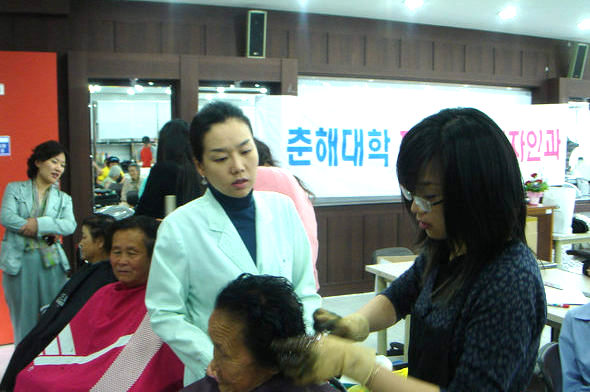 한 학생이 최영진 교수(왼쪽 흰가운) 지도로 할머니 머리를 손질하고 있다. 춘해대 제공