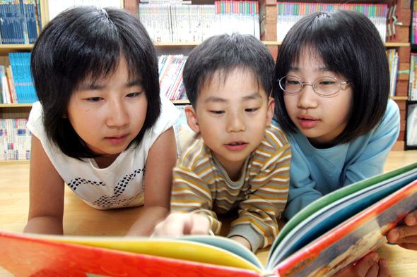 민주, 승우, 소정 삼남매(왼쪽부터)가 서울시 휘경동 집 거실에서 나란히 엎드려 동화책을 보며 이야기를 나누고 있다. 이정아 기자