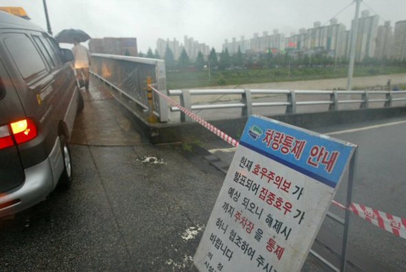 서울.경기 지역에 100mm 이상의 집중호우가 내려 호우주의보가 발효된 가운데 경기도 의정부시 중랑천이 범람, 천변 주차장에 있던 차량 320여대를 견인차량으로 끌어낸 뒤 차량통행을 통제했다. (연합뉴스)