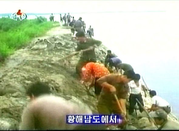 북한 황해남도 주민들이 큰물로 무너진 둑을 다시 쌓느라 흙을 실어나르고 있다. 북한 언론매체들이 나흘째 수해 상황을 보도하고 있는 가운데, <조선중앙텔레비전>은 이번 수해에서는 처음으로 화면으로 피해 모습을 전했다.       조선중앙텔레비전 촬영/연합뉴스