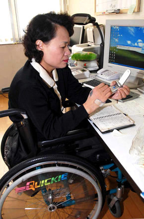 전자상거래로 생계를 유지하는 중증 장애인 신숙이 사장이 문자메시지를 보내기 위해 손에 고정한 볼펜으로 휴대전화 버튼을 누르고 있다.