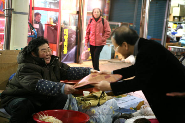 역전시장에서 노점을 하는 한 할머니가 울산교회 정근두 목사로부터 전기방석을 받고 기뻐하고 있다. 울산교회 제공
