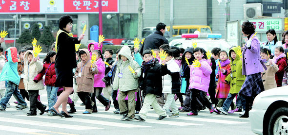 지난해 3월 서울 한 초등학교 1학년생들이 플라스틱으로 만든 ‘엄마손’을 든 채 횡단보도를 건너는 체험을 하고 있다. <한겨레> 자료사진