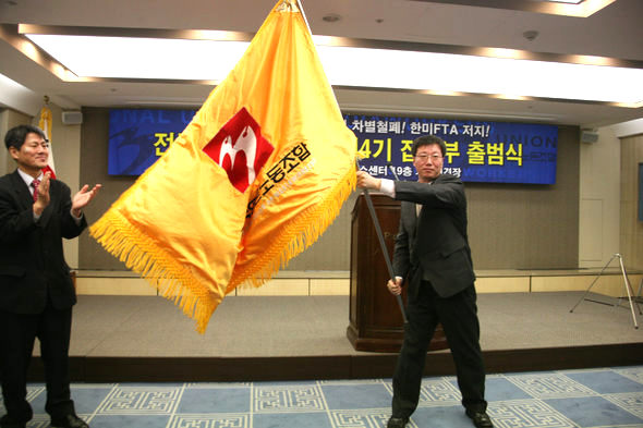 이준안(오른쪽) 신임 언론노조 위원장이 지난 3월7일 서울 태평로 한국언론회관에서 열린 이취임식에서 신학림 전 위원장으로부터 건네받은 깃발을 흔들고 있다. 언론노조 제공
