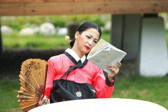 촬영 중 부채로 땀을 식히며 대본을 보고 있는 한고은.