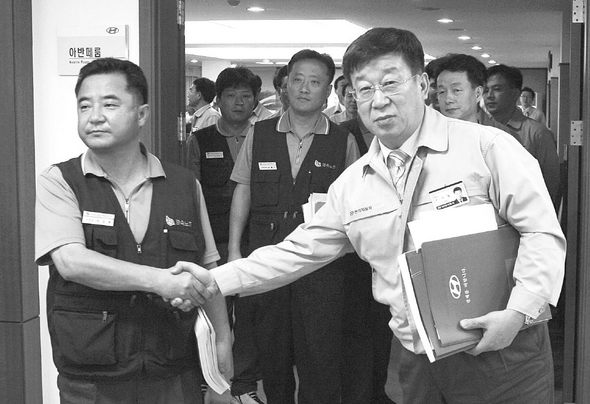 현대자동차 노조 이상욱 지부장(왼쪽)과 윤여철 사장이 4일 오후 울산 현대자동차 본관 1층에서 노사 협상에 잠정 합의한 뒤 협상장을 나서며 악수하고 있다. 울산/연합뉴스