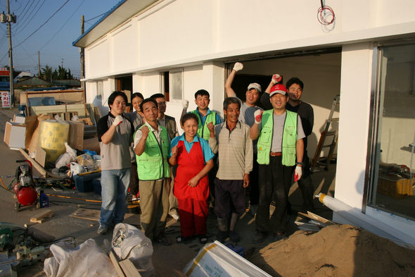충남 서산 간월도 김종관씨 집 수리봉사에 나선 희망의 러브하우스 자원봉사자들이 6일 김씨 부부(앞줄 가운데)와 파이팅을 외치고 있다.