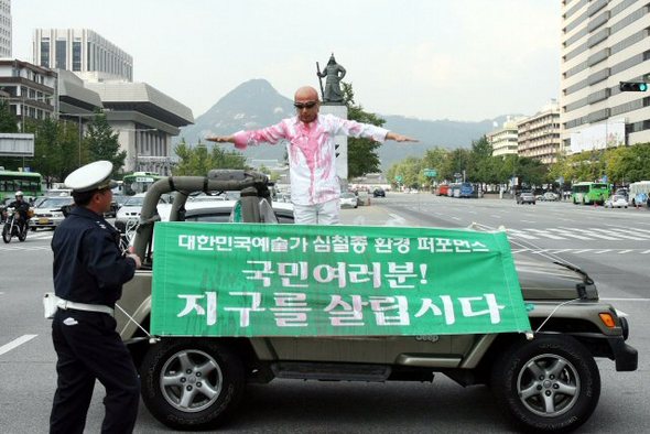 15일 오후 서울 광화문 이순신장군 동상 앞에서 행위예술가 심철종씨가 지구를 살리자는 의미로 온몸에 붉은 물감을 뿌리는 퍼포먼스를 하다 경찰의 제지를 받고 있다. 연합