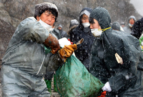충남 태안군 모항리 주민 임순덕(66, 왼쪽)씨가 기름을 닦은 천이 든 부댓자루를 옮기는 것을 한 자원봉사자가 돕고 있다. 태안/박종식 기자 <A href="mailto:anaki@hani.co.kr">anaki@hani.co.kr</A>