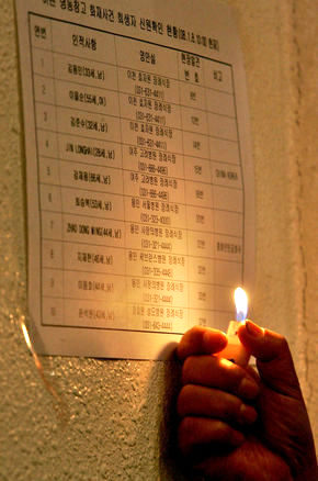 경기 이천시 냉동창고 화재 사고 희생자들의 합동분향소가 마련된 이천시민회관에서 8일 오전 한 유가족이 라이터 불을 켜고 신원이 확인된 사망자들의 명단을 살펴보고 있다. 이천/이종근 기자 <A href="mailto:root2@hani.co.kr">root2@hani.co.kr</A>