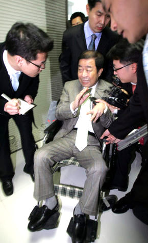 이명박 대통령 당선인의 처남 김재정씨가 31일 오후 ㈜다스와 ‘도곡동 땅’ 차명소유 의혹에 대한 조사를 받기 위해 서울 역삼동 ‘이명박 특검’ 사무실에 휠체어를 탄 채 나와 취재진의 질문을 받고 있다. 도곡동 땅 매각 대금을 관리해 온 이병모씨가 김씨의 뒤에서 휠체어를 밀고 있다.장철규 기자 <A href="mailto:chang21@hani.co.kr">chang21@hani.co.kr</A>