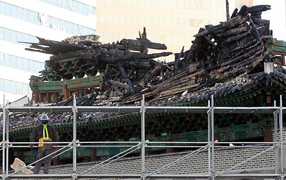 12일 오전 숭례문 화재 전소 현장에서 펜스 설치 작업을 하던 한 공사 관계자가 불탄 남대문을 바라보고 있다. 연합뉴스 12일 오전 숭례문 화재 전소 현장에서 펜스 설치 작업을 하던 한 공사 관계자가 불탄 남대문을 바라보고 있다. 연합뉴스
