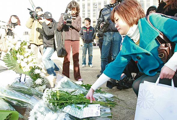 12일 오후 한 시민이 서울 숭례문 화재현장에 국화꽃을 가져다 놓고 있다. 연합뉴스 12일 오후 한 시민이 서울 숭례문 화재현장에 국화꽃을 가져다 놓고 있다. 연합뉴스