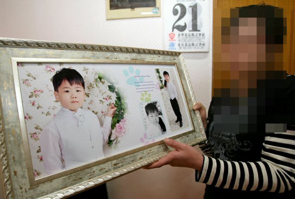 지난 11일 울산에서 우영진군의 사진을 계모인 오모(30)씨가 들어 보이고 있다. 당시 오씨는 우 군을 찾아달라고 호소했다. 연합