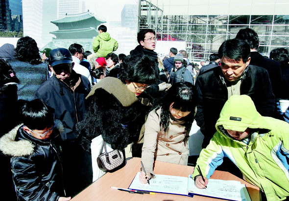 문화재 사랑 계속되길… / 17일 낮 숭례문 화재현장을 찾은 한 가족이 잿더미로 변한 숭례문을 살펴본 뒤 방명록에 글을 남기고 있다. 장철규 기자 <A href="mailto:chang21@hani.co.kr">chang21@hani.co.kr</A>