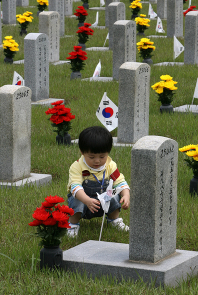 현충일인 6일 오전 서울 동작동 국립서울현충원을 찾은 한 어린이가 묘비 앞에 엉킨 채 꽂혀 있는 태극기를 풀고 있다. 박종식 기자 anaki@hani.co.kr