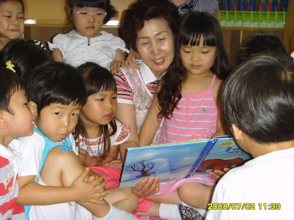 울산 동구 방어동 하나유치원 보조교사인 이명애 할머니가 유치원생들한테 둘러싸여 구수한 목소리로 동화를 들려주고 있다.