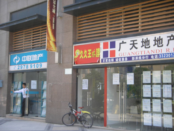 선전시 바오안구의 한 아파트 단지 앞 부동산 중개업소 직원이 지난 20일 거리를 내다보고 있다. 부동산 가격 급락 속에 매매가 사라지면서 문을 닫는 중개업소들이 속출하고 있다.