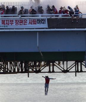 지난 18일 오후 서울 잠실철교 위에서 농성을 벌인 시각장애인 안마사 28명 중 한 명이 경찰의 검거 작전이 시작되자 강물로 뛰어내리고 있다.  연합뉴스