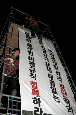20일 밤 서울 금천구 가산동 기륭전자 본사 정문 앞에서 기륭전자 비정규직 노동자와 시민들이 함께 설치한 철탑을 구사대와 용역원들이 흔들며 철거하려 하자, 구조물 위에서 시위를 벌이던 김소연 금속노조 기륭전자분회장(뒷모습이 보이는 이)이 “원하는 대로 죽여봐”라고 외치며 구조물에 가까스로 매달려 있다. 김경호 기자 jijae@hani.co.kr