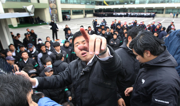 5일 인천 부평구 대우자동차판매 본사에서 회사가 동원한 용역업체 경비원들이 건물에 갇힌 동료에게 음식을 전달하려는 노조원들에게 손가락질하며 실랑이를 벌이고 있다. 뒤쪽 건물 앞에는 노사 충돌을 막는다는 명분으로 출동한 경찰 전경대원들이 서 있다.  인천/김진수 기자 jsk@hani.co.kr