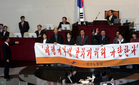 2006년 민주노동당 의원들이 임채정 국회의장이 직권상정한 비정규직 관련 3법의 표결을 막기 위해 국회 본회의장에서 발언대를 점거하며 규탄하고 있다.  김종수 기자 <A href="mailto:jongsoo@hani.co.kr">jongsoo@hani.co.kr</A>