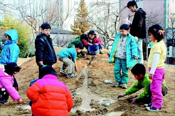 생태유아교육을 실천해 오고 있는 부산대 부설 어린이집 아이들이 어린이집 마당에 있는 모래언덕에서 물을 부으며 모래놀이를 하고 있다. <한겨레> 자료사진