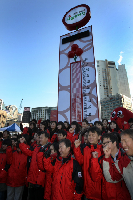 3일 오전 서울광장에서 사회복지공동모금회 주최로 열린 희망 2009 나눔 캠페인 ‘사랑의 행복 온도탑‘ 행사에서 모금회 관계자들이 손으로 사랑의 하트 표시를 하고 있다. 사랑의 행복 온도탑은 전국에서 모금된 이웃사랑 성금에 따라 온도가 올라가는 것으로 20억8천5백만원이 모금될 때마다 1도씩 올라가 모금 목표인 2,085억원에 도달하면 100도가 되는 나눔 온도탑이다.