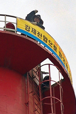 이영도 민주노총 울산본부 수석부본부장과 김순진 현대미포조선 현장노동조직 ‘현장의 소리’ 의장이 24일 오전 6시40분께부터 울산 동구 방어동 예전부두 염포소각장 100ｍ 높이 굴뚝에 올라가 고공농성을 벌이고 있다.울산/연합뉴스