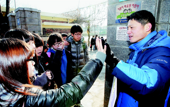 일제고사 대신 체험학습을 허락했다고 파면된 정상용 전 구산초등학교 교사가 23일 서울 은평구 구산초등학교 앞에서 1인시위를 벌이며 등교하는 아이들과 손을 잡고 인사하고 있다.  이종근 기자root2@hani.co.kr