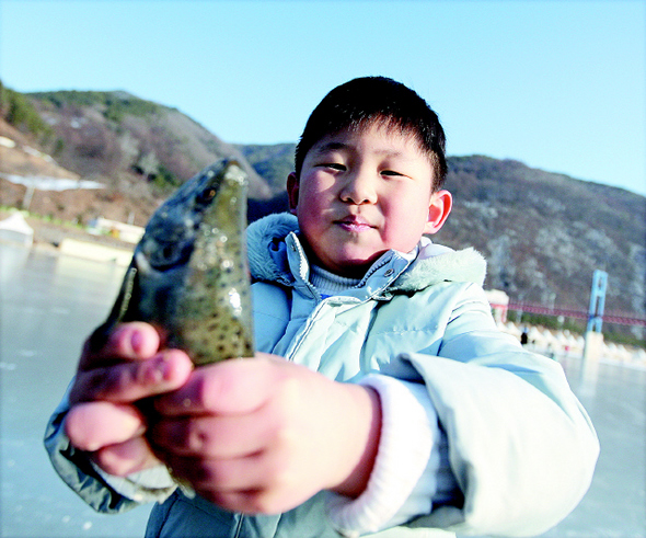 화천천 얼음판에서 산천어를 맨손으로 들고 흐뭇해하는 엄태양(7·화천초1) 어린이.