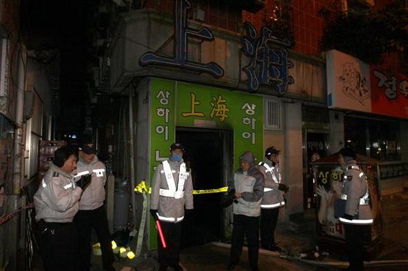 경찰이 14일 오후 불이 나 8명이 숨진 부산 영도구 남항동 상하이 노래주점의 출입구를 지키고 있다. 부산/연합뉴스 경찰이 14일 오후 불이 나 8명이 숨진 부산 영도구 남항동 상하이 노래주점의 출입구를 지키고 있다. 부산/연합뉴스