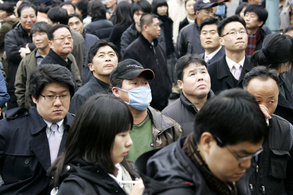 서울 용산구 한강로2가 철거민 참사 현장 주변을 지나던 시민들이 21일 오후 경찰 감식 작업이 벌어지는 참사 현장을 굳은 표정으로 올려다보고 있다.  김명진 기자