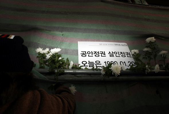서울 용산구 한강로2가 철거민 사망사고 현장 가림막에, 20일 오후 시민들이 희생자들을추모해 꽂아놓은 국화꽃과 정부의 강경 진압을 비난하는 손팻말이 놓여 있다. 이종근 기자 root2@hani.co.kr