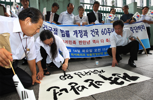 지난해 8월 14일 서울 세종로 정부중앙청사 앞에서 행위예술가 시온 칸(본명 배희권·앞줄 왼쪽 두번째)씨가  ‘8·15 건국절 법률개정 추진과 건국 60주년 기념사업’을 비판하며 ‘건국반만년, 정부수립 89주년’이라고 붓글씨를 쓰고 있다.  김종수 기자 <A href="mailto:jongsoo@hani.co.kr">jongsoo@hani.co.kr</A>