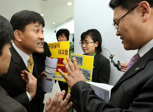 한국대학교육협의회가 11일 오후 서울 마포구 상암동 케이지아이티(KGIT)빌딩에서 연 ‘2011학년도 대입전형 기본사항 수립을 위한 세미나’ 행사장 앞에서, 엄민용 전국교직원노동조합 대변인(오른쪽)과 대교협 관계자들이 입씨름을 벌이고 있다. 이들 뒤편에서 참교육을 위한 전국학부모회 회원들이 대교협의 입시안을 비판하는 손팻말 시위를 벌이고 있다. 김종수 기자 jongsoo@hani.co.kr