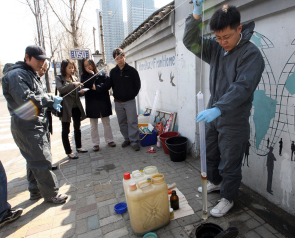 한국농어촌공사 직원들이 23일 오후 미군 기지가 있는 서울 용산구 삼각지역 주변 거리에서 지하수 관측정 뚜껑을 열고 기름 제거 작업을 하고 있다. 신소영 기자 viator@hani.co.kr