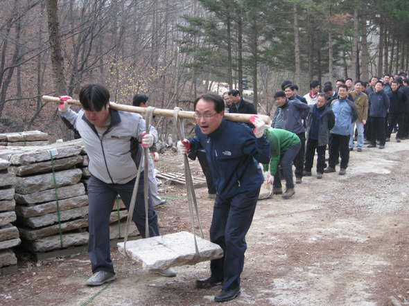 야외 모닝아카데미에 앞서 직원들이 교육장용 박석을 목도로 운반하고 있다.
