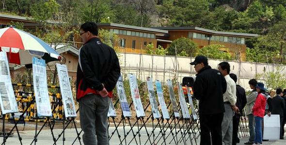 경남 김해시 봉하마을의 노무현 전 대통령 집을 찾은 관광객들이 26일 오후 집 앞 주차장에 설치된 전시물을 둘러보고 있다. 이 전시물은 노 전 대통령을 지지하는 사람들이 만들어 세운 것이다.  김해/연합뉴스