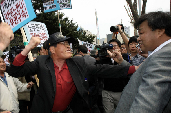 노무현 전 대통령의 구속수사를 주장하는 보수단체 소속 회원(왼쪽)이 30일 오후 서울 서초동 대검찰청 앞에서 노 전 대통령 지지자를 향해 주먹을 휘두르고 있다. 이들은 노 전 대통령을 응원하는 내용의 펼침막을 뜯어내려다 이를 막는 지지자들과 실랑이를 벌였다.  이정아 기자