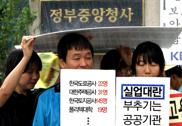 민생민주국민회의 회원과 민주노총 소속 비정규직 노동자들이 6일 오후 서울 세종로 정부중앙청사 정문 앞에서 소나기를 맞으며 정부의 공공부문 비정규직 ‘기획해고’를 비판하고 있다. 이들은 “정부가 ‘100만 해고 대란설’을 입증이라도 하려는 듯 공공부문의 비정규직 대량 해고를 방치하고 있다”고 주장했다.  김종수 기자 jongsoo@hani.co.kr