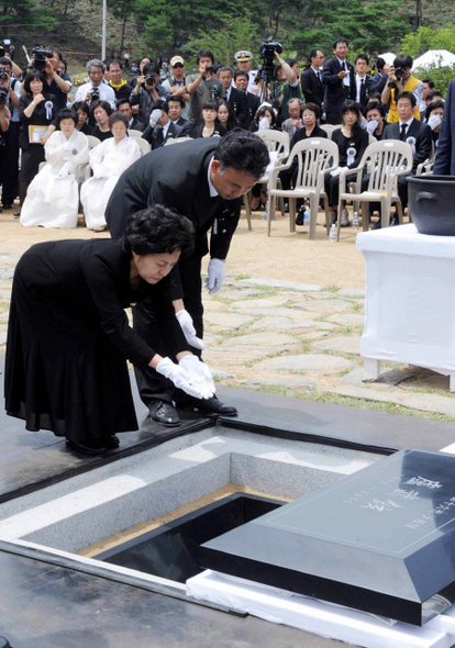 <b>편히 쉬세요</b> 노무현 전 대통령의 부인 권양숙씨가 10일 오후 경남 김해시 진영읍 봉하마을에서 열린 노무현 전 대통령의 안장식에서 관 위에 너럭바위를 덮기 전 흙 한줌을 뿌리고 있다. 김해/사진공동취재단
