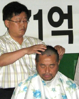  경기도의회 민주당 대표인 윤화섭(안산5) 의원이 21일 오전 경기 수원시 팔달구 도의회 1층 로비에서 민주당과 민주노동당 등 동료 의원들이 지켜보는 가운데 “차별 없는 무상급식 실현을 못 지켜내 죄송하다”며 삭발을 하고 있다.