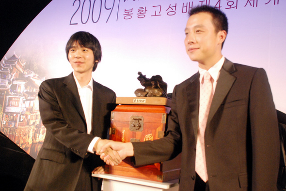 한국의 이세돌(왼쪽) 9단과 중국의 구리 9단이 15일 베이징 장성호텔에서 열린 2009 봉황고성배 조인식에서 악수하고 있다.  사이버오로 제공