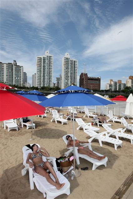 5일 서울 광진구 뚝섬 야외수영장에 문을 연 ‘강변 선탠장’에서 시민들이 여름 햇살을 맞으며 선탠을 즐기고 있다. 모래 위에 의자·파라솔 100개와 샤워부스, 탈의실 등 편의시설이 마련된 강변 선탠장의 이용료는 1인당 3천원이다. 연합뉴스