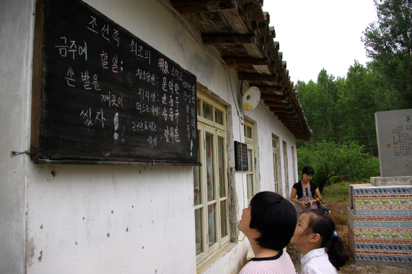 12일 중국 연변조선족자치주 용정시 명동촌에 있는 윤동주 시인 생가에서 동포 김해응씨의 조카 해옥양이 누군가 칠판에 장난으로 써놓은“청소당번 문익환, 지각생 윤동주”글귀들을 보면서 환하게 웃고 있다. 유강문 특파원